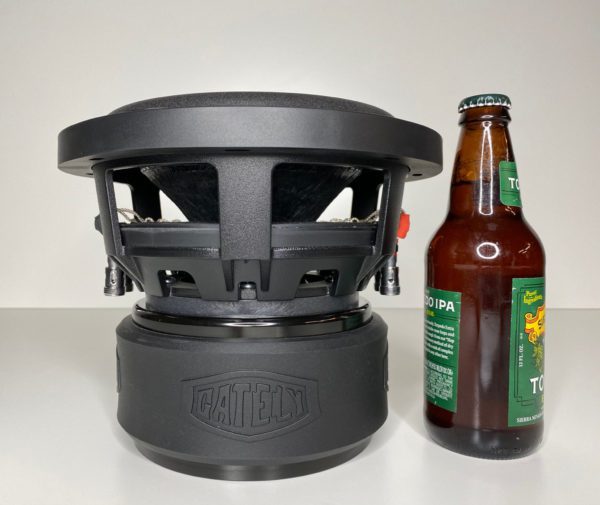 A beer bottle next to a Gately Audio Alpha 8 Inch Subwoofer.