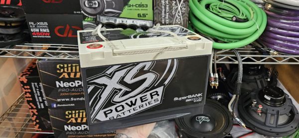 A person is holding a box of B-STOCK XS Power SB630-34 Superbank in a store.