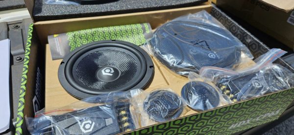 A box of Soundqubed HDX Series 6.5" Component Set (Pair) car speakers in a parking lot.