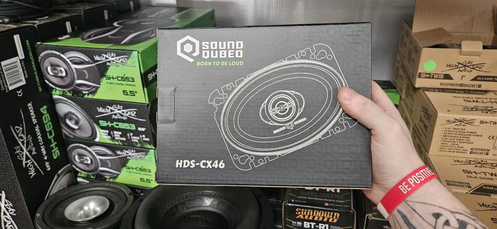 A person holding up a box of Soundqubed HDS Series 4x6" Coaxial 2-way Speakers (Pair).
