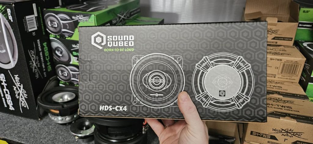 A person holding a box of Soundqubed HDS Series 4" Coaxial 2-way Speakers (Pair) in a store.
