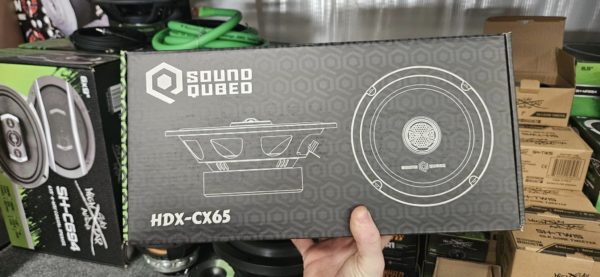 A person is holding up a box of Soundqubed HDX Series 6.5 inch 2-way Coaxial Speakers (Pair).