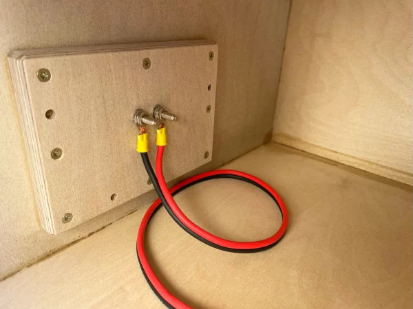 A red wire connected to the Adire Audio Performance Series - Dual 12" subwoofer enclosure.