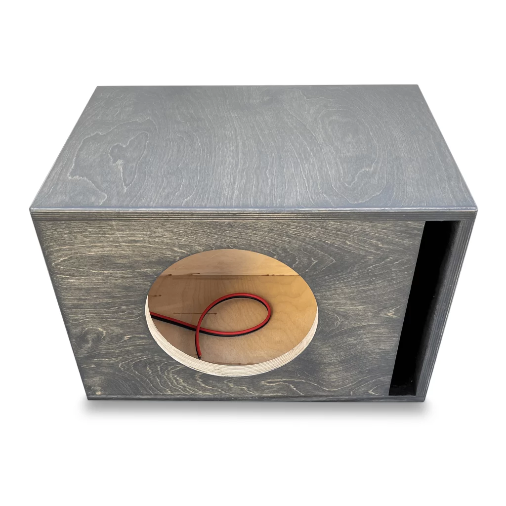 A performance subwoofer enclosure made of wood with a hole in it, designed for use with the Adire Audio Performance Series – Single 10″ 1.25 Cf Net Ported Enclosure subwoofers.