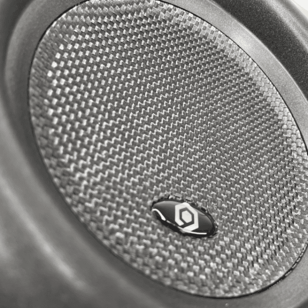 A black and white photo of a Soundqubed HDX 6.5 Inch D4 Subwoofer in a car.